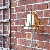 Polished Brass Bell with Rope Lanyard on Brick Wall