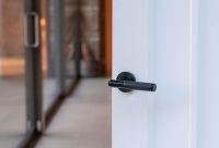 Sleek Black Textured Unsprung Lever Door Handle on Beehive Rose in Situ