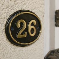 Close up of polished brass & black oval house number