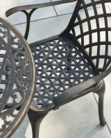 Close up of intricate seat detail on antique bronze outdoor dining set