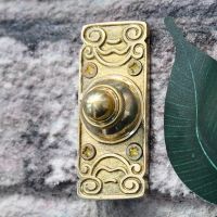 Side view of ornate polished brass doorbell push