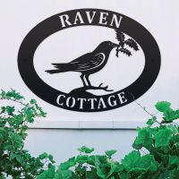 Raven & Holly Iron Oval House Sign on a White Wall