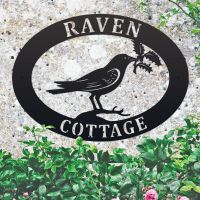 Raven & Holly Iron Oval House Sign on a Stone Wall