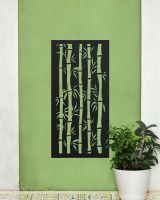 Black "Bamboo Garden Wall Art" on a green garden wall next to a potted plant