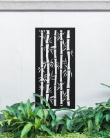Black "Bamboo Garden Wall Art" on a white garden wall surrounded by plants