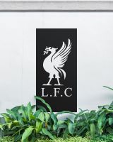 Black "Liver Bird Wall Art" on a white garden wall behind garden plants 