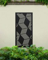 Black "Geometric Cube Wall Art" on a cream coloured garden wall surrounded by garden plants