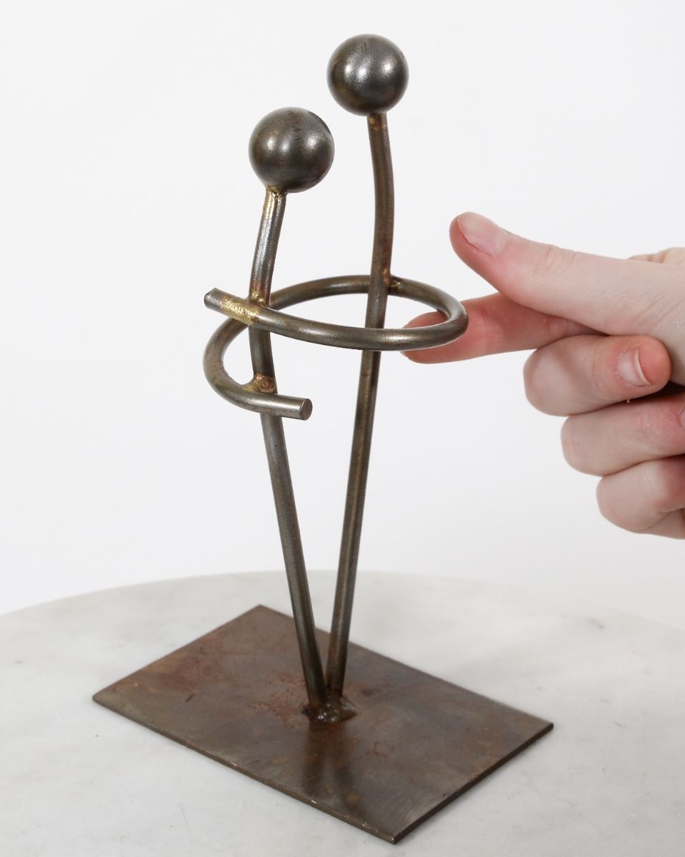 "Embrace" Upcycled Metal Art Ornament with hand in shot for scale