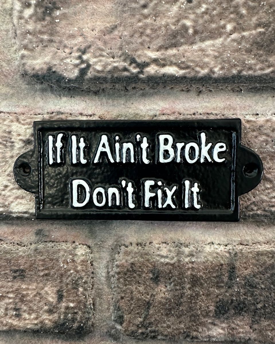 "If it ain"t Broke Don"t Fix It" Traditional Cast Iron Wall Sign mounted on a brick wall