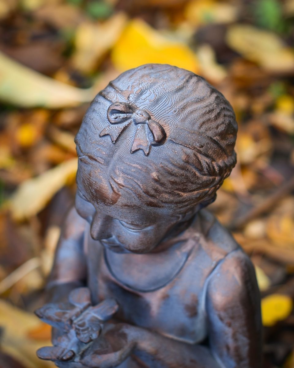 "Meadow"s Offering" Girl Holding Butterfly Resin Garden Sculpture close up of bow on head