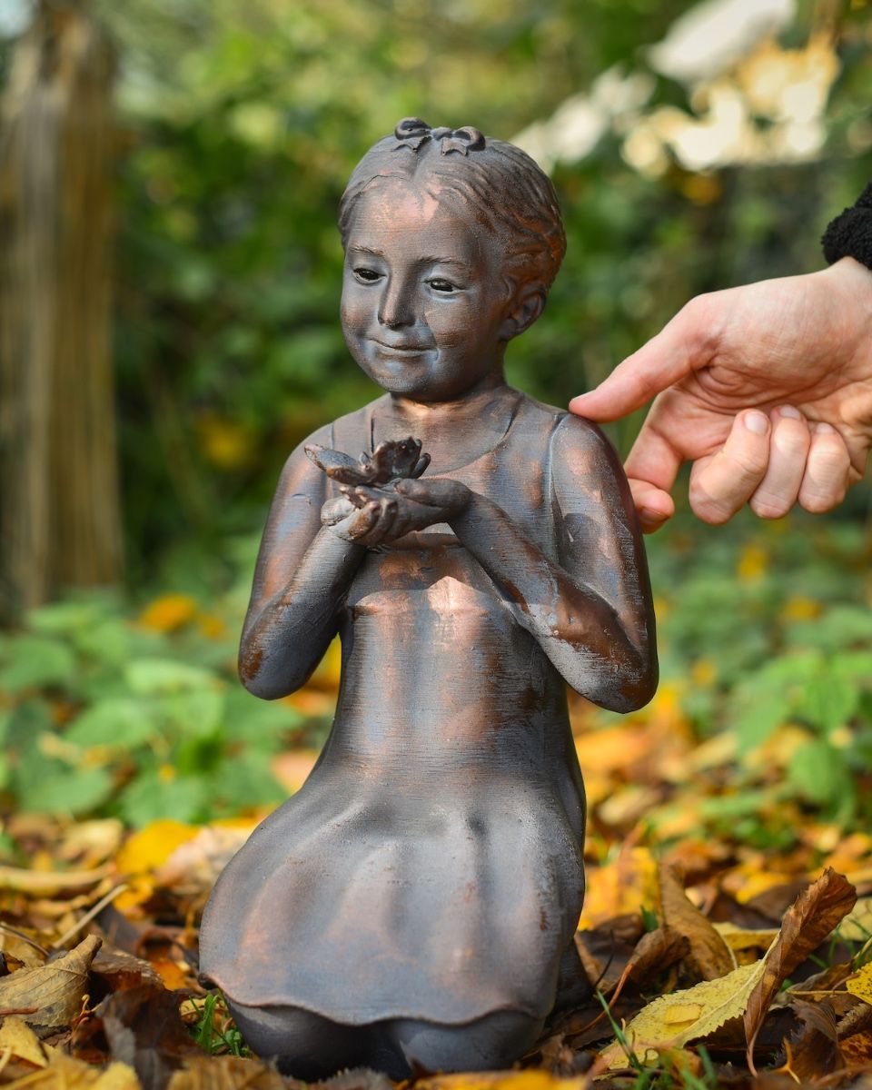 "Meadow"s Offering" Girl Holding Butterfly Resin Garden Sculpture with hand in shot for scale