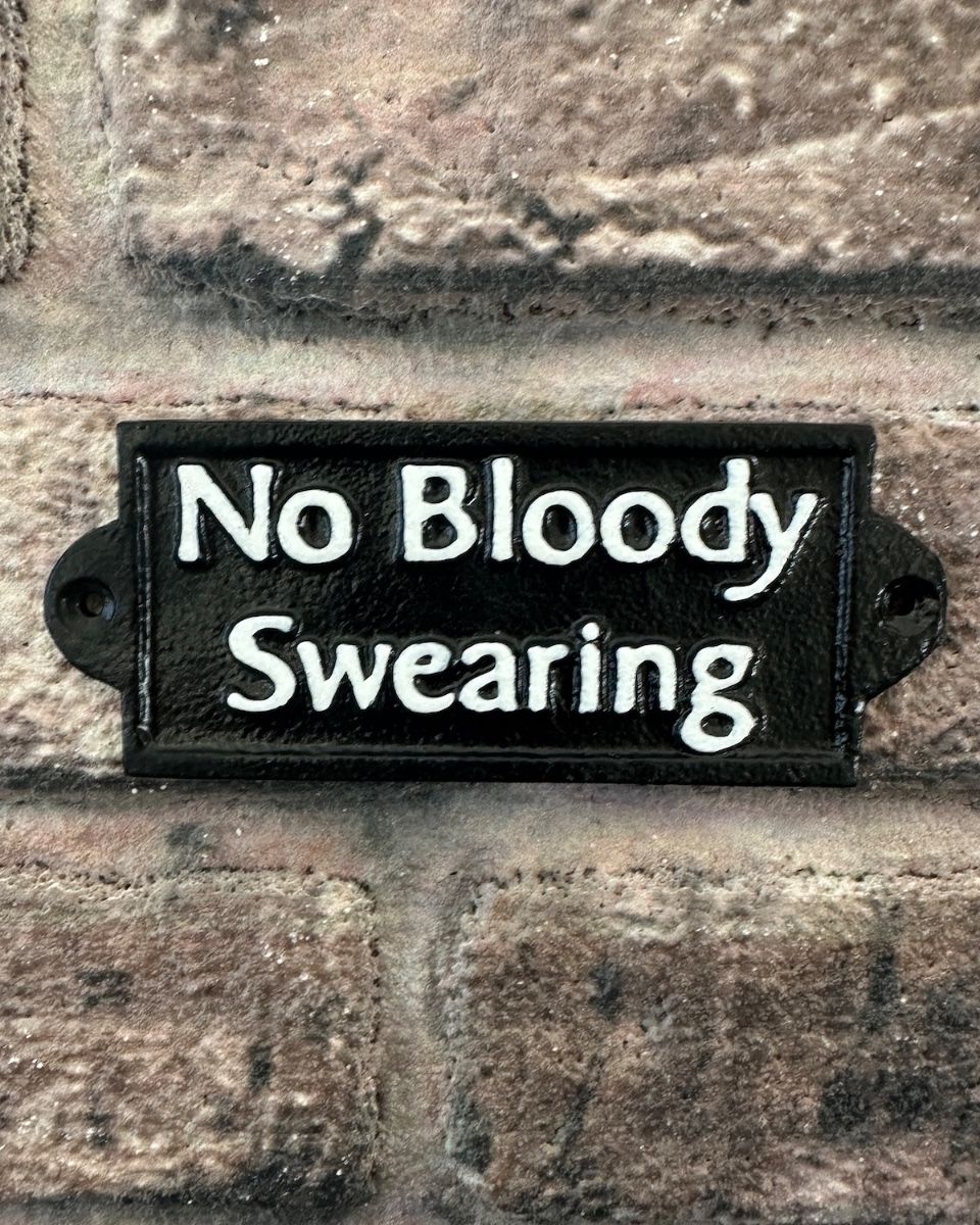 "No Bloody Swearing" Traditional Cast Iron Wall Sign mounted on a brick wall