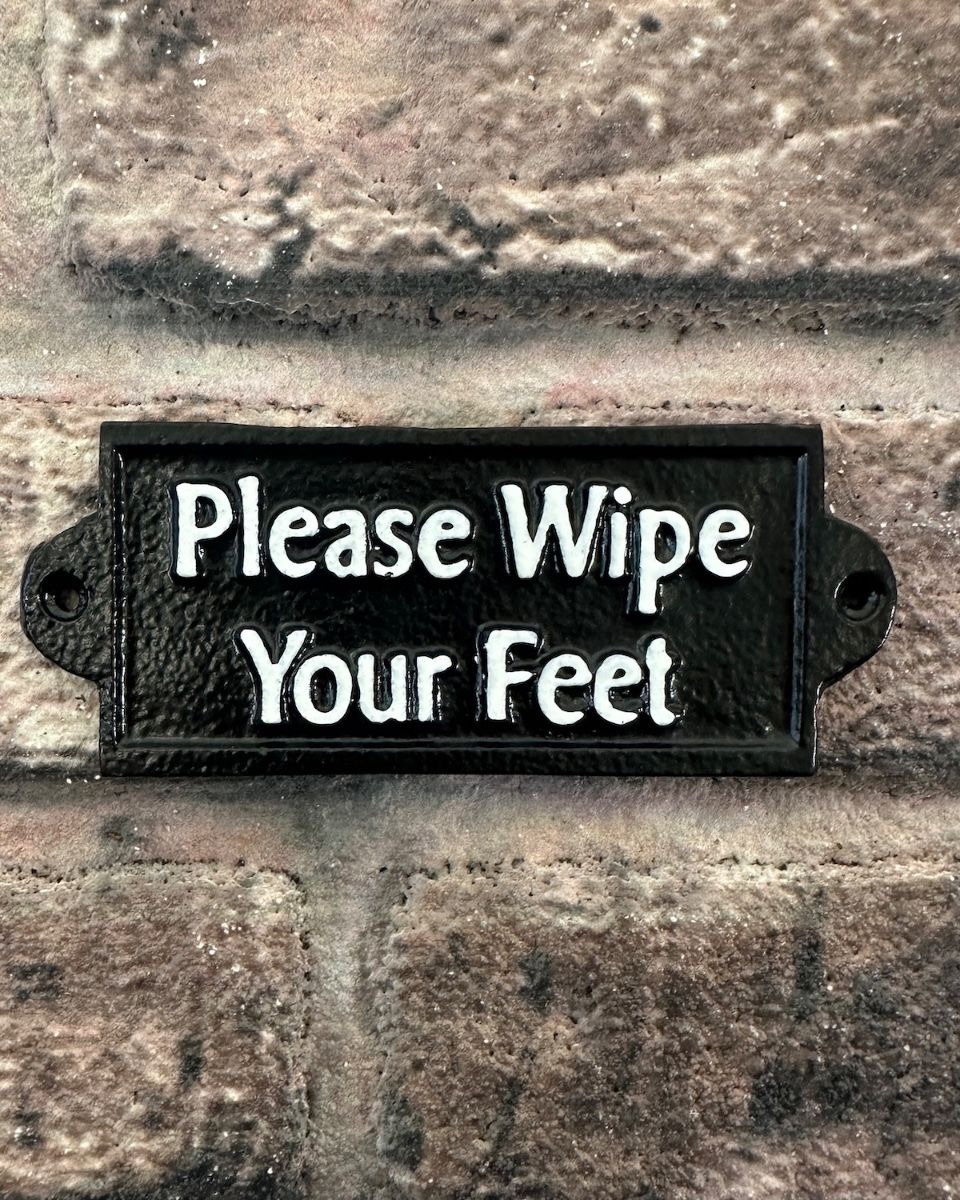 "Please Wipe your Feet" Traditional Cast Iron Wall Sign mounted on a wall