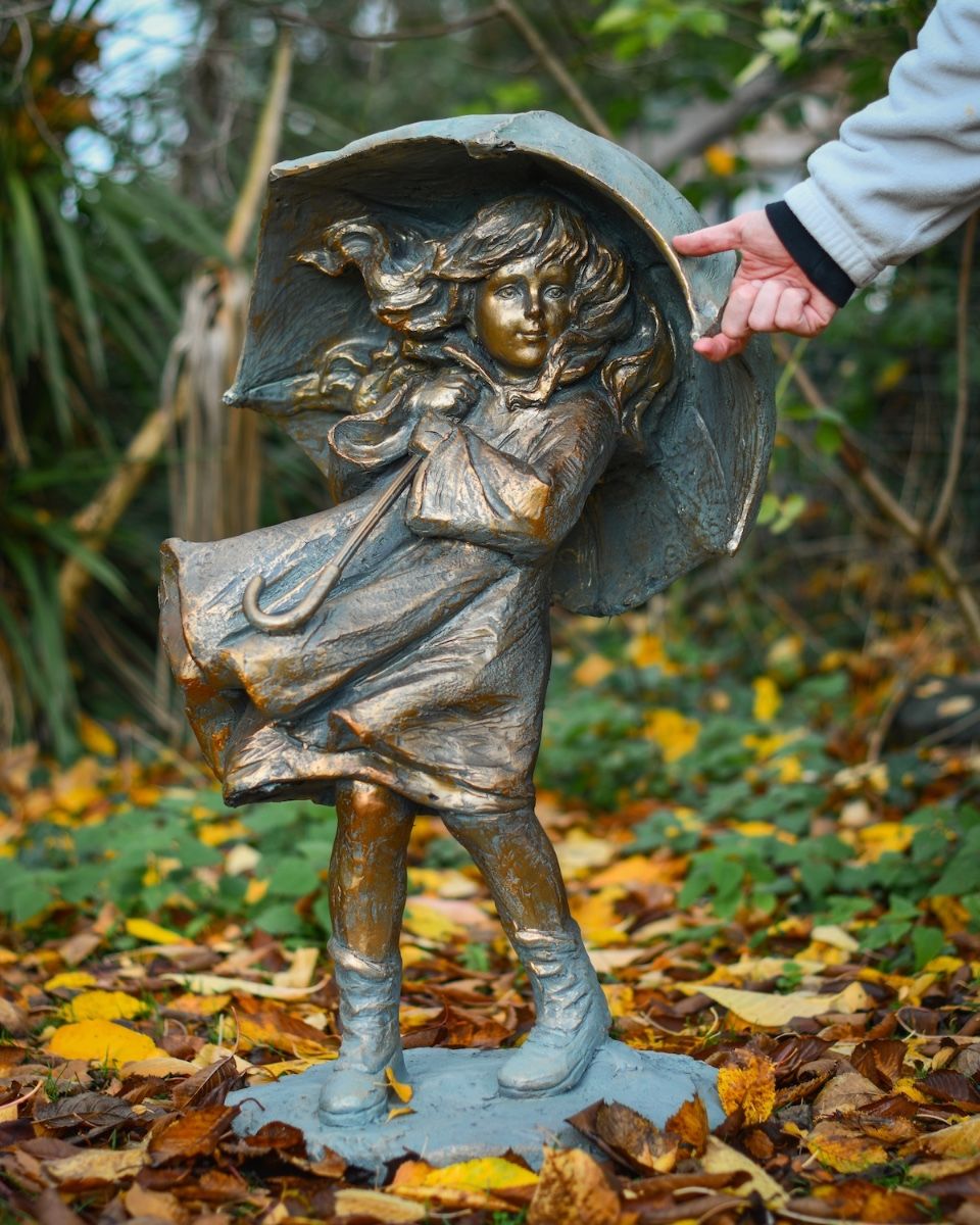 "Rain or Shine" Girl with Umbrella Resin Garden Sculpture Brass and Verdigris Finish with hand in shot for scale