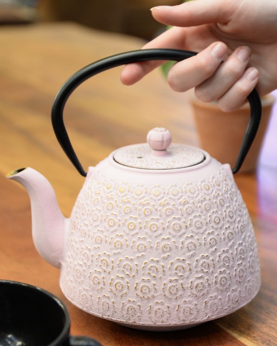 "Sakura" Cast Iron Japanese Teapot with a Pink Finish with Hand in Shot for Scale