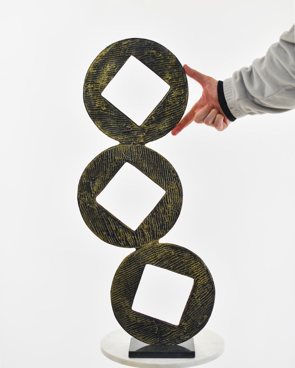 "Triple Aspect" Cast Aluminium Home Ornament - Black and Gold with hand in shot for scale