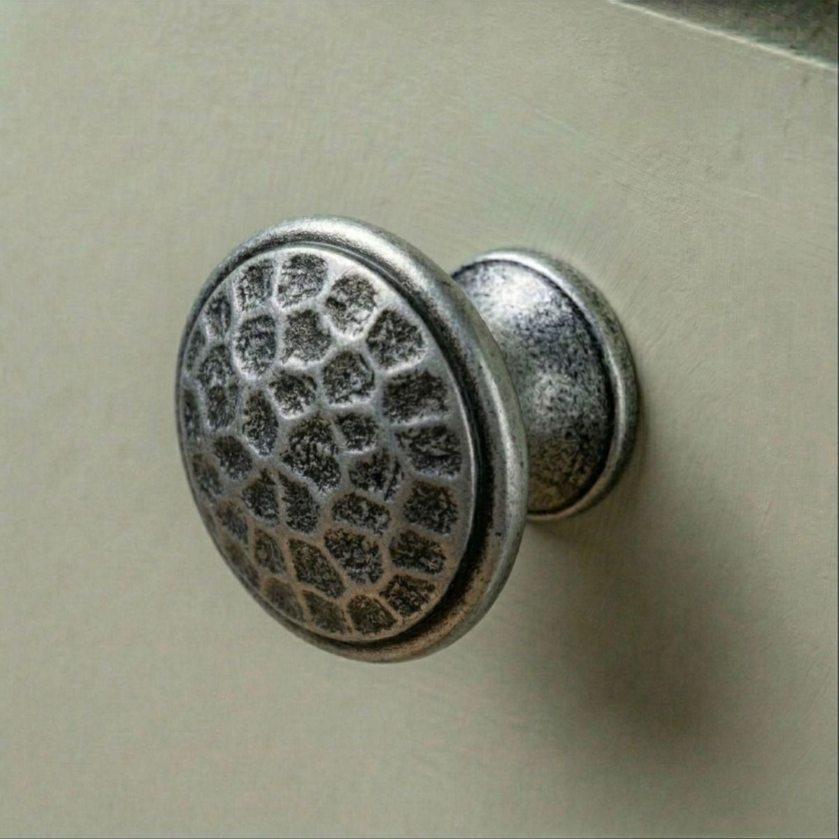 A 40mm Hammered Pewter Cabinet Knob Mounted on a Contemporary Sage Green Kitchen Cabinet - Digital Illustration