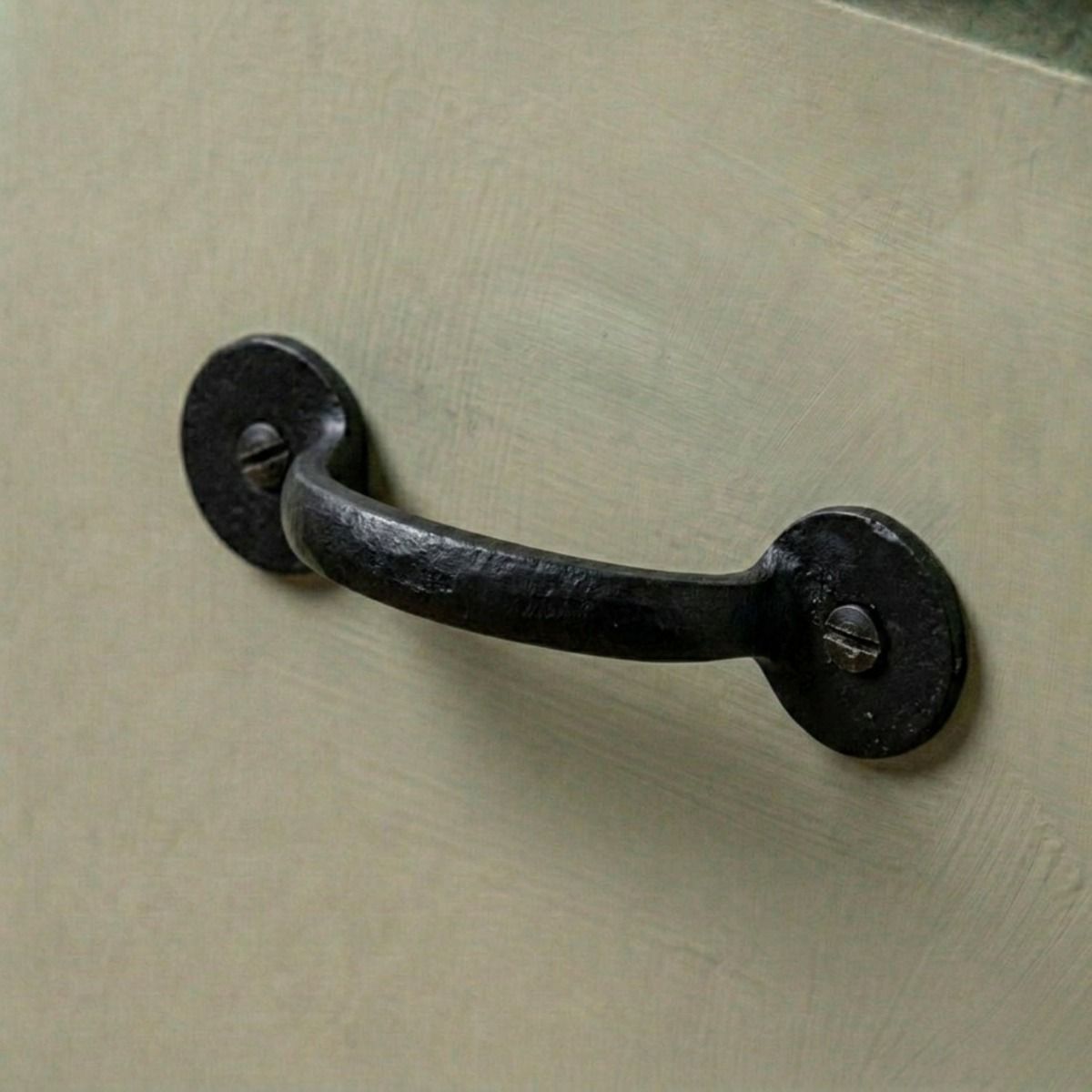 A Black Iron Round Plated Pull Handle Mounted on a Green Kitchen Cabinet - Digital Illustration 
