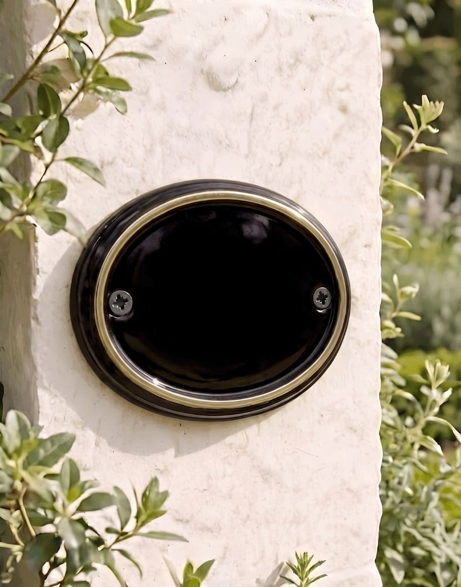A Blank Brass & Black Oval House Number Plaque Mounted on a Sunny White Property Wall - Digital Illustration