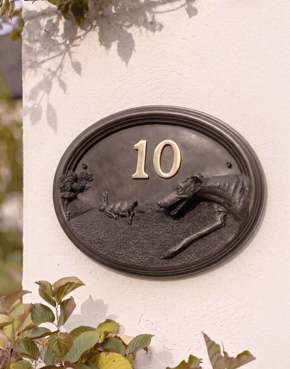 A Number 10 Greyhound House Number Sign in a Bronze Finish Mounted on a Cream Coloured Cottage Wall - Digital Illustration 