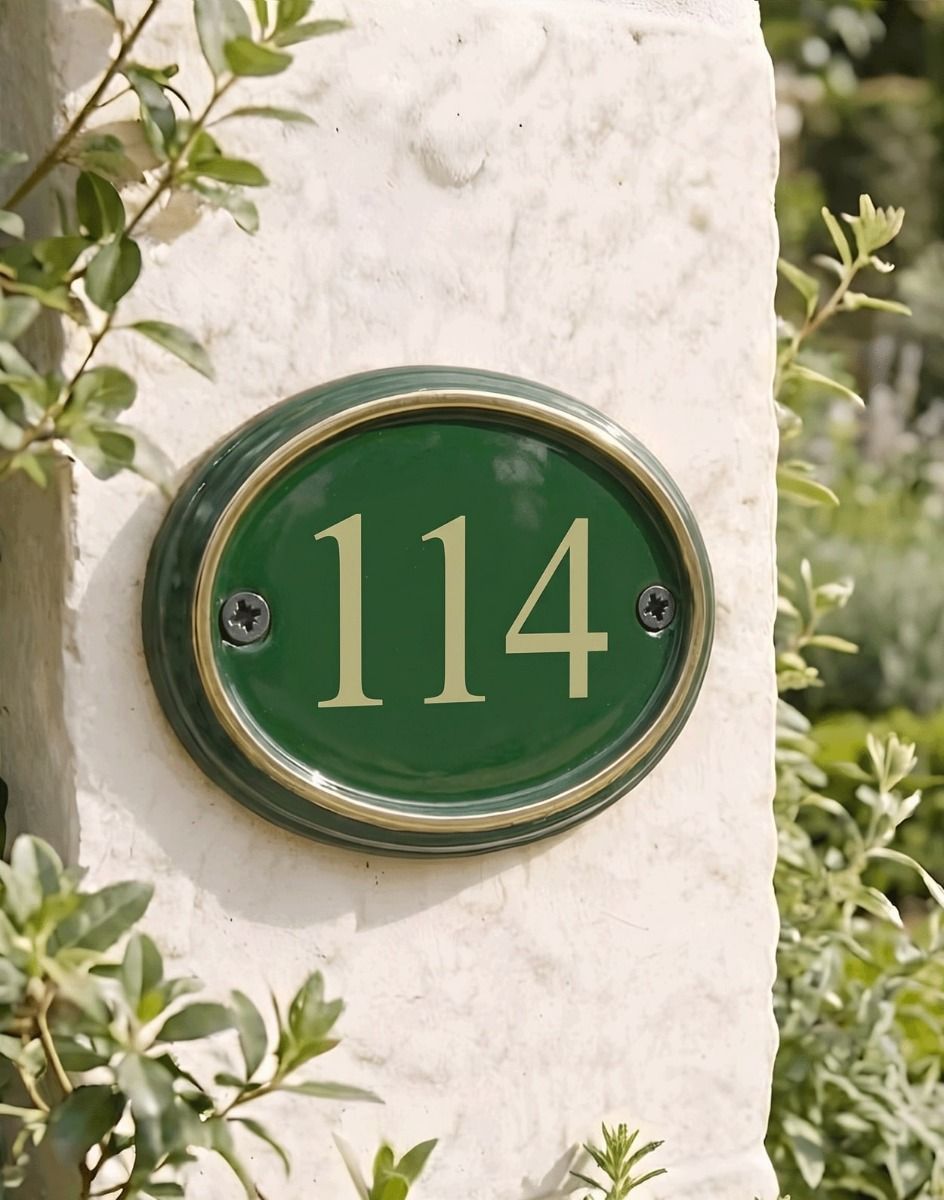 A Number 114 in Vinyl Polished Brass & Green Cast Oval House Number Sign Mounted on a Cream Coloured Building Wall - Digital Illustration