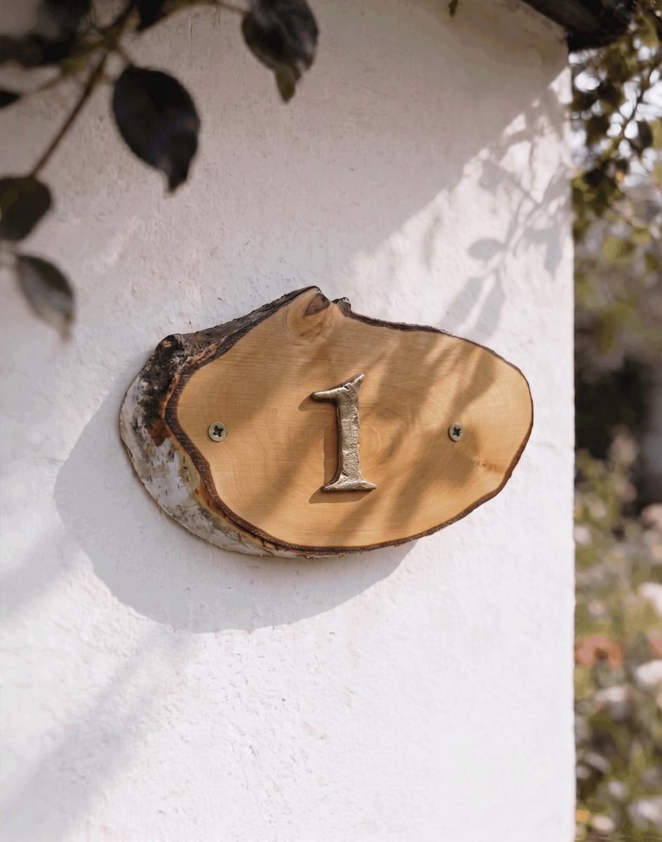 A Number 1 Natural Hard Wood Rustic House Number Sign Mounted on a Sunny White Coloured Cottage Wall - Digital Illustration 