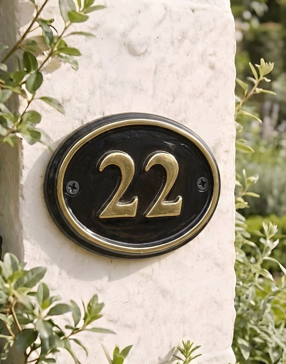 A Number 22 Polished Brass & Black Oval House Number Sign Mounted on a Cream Coloured Property Wall - Digital Illustration