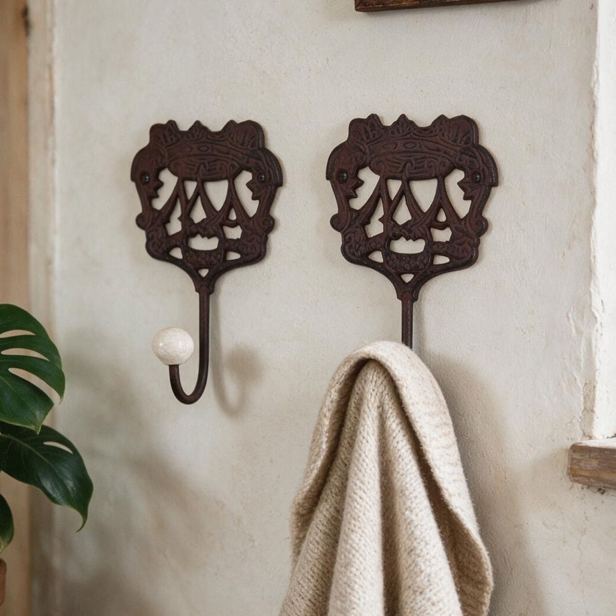 A pair of "Royal Camelot" Cast Iron Hooks Fitted onto a White Wall in a Traditional Home - Digital Illustration