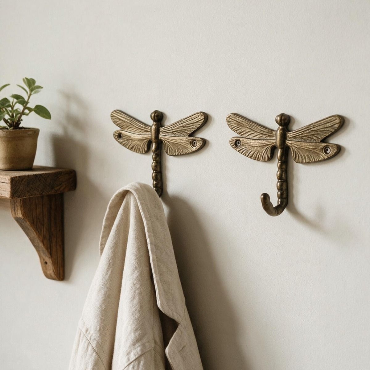 A Pair of Antique Brass Dragonfly Wall Hooks Attached to a Bright Cream Coloured Hallway Wall - Digital Illustration 