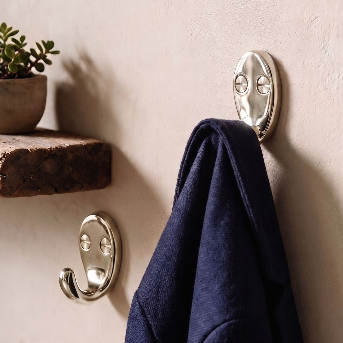 A Pair of Polished Nickel Single Pronged Coat Hooks Supporting a Blue Jacket on a Wall - Digital Illustration 