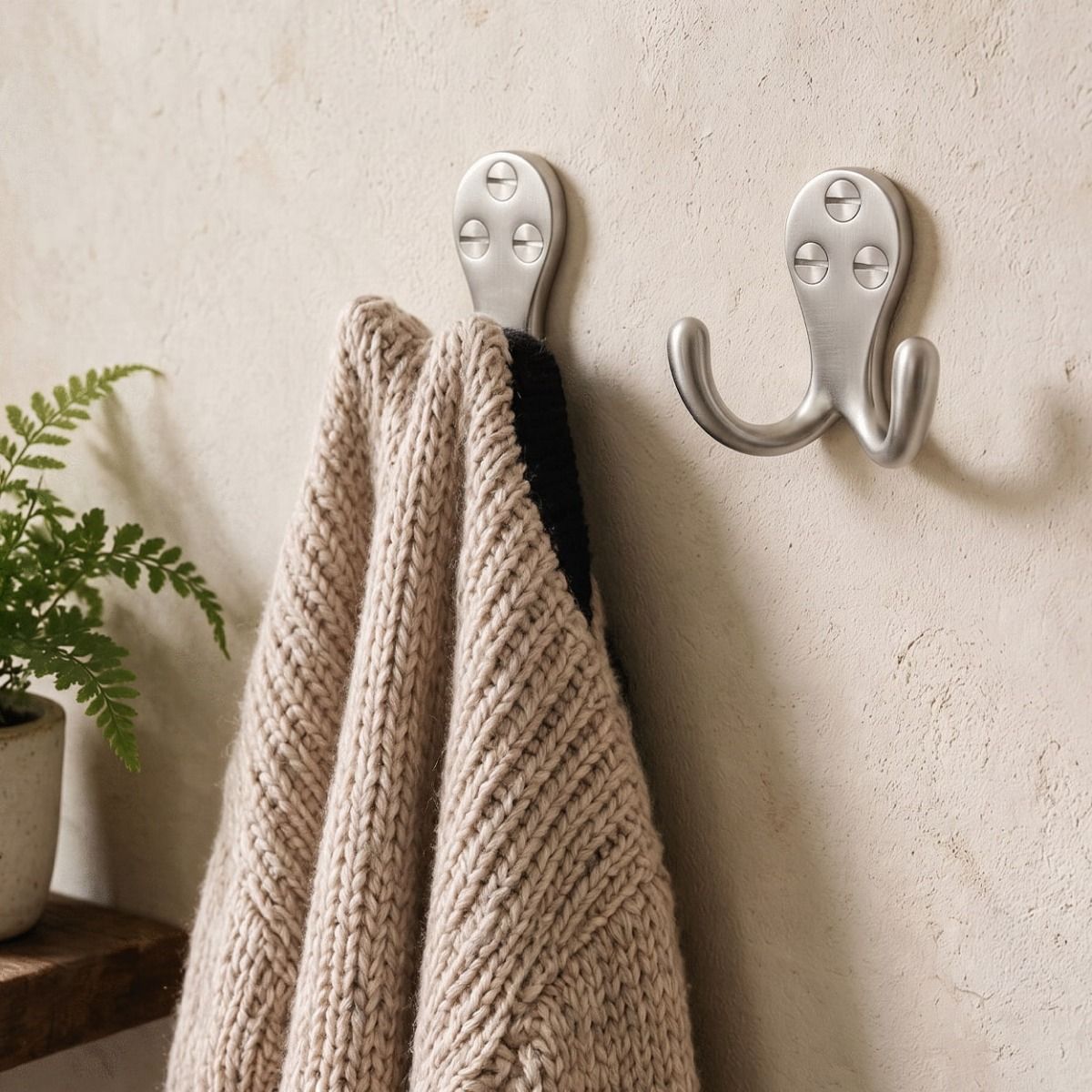 A Pair of Satin Chrome Double Pronged Coat Hook Fitted onto a Wall Holding a Jumper - Digital Illustration 