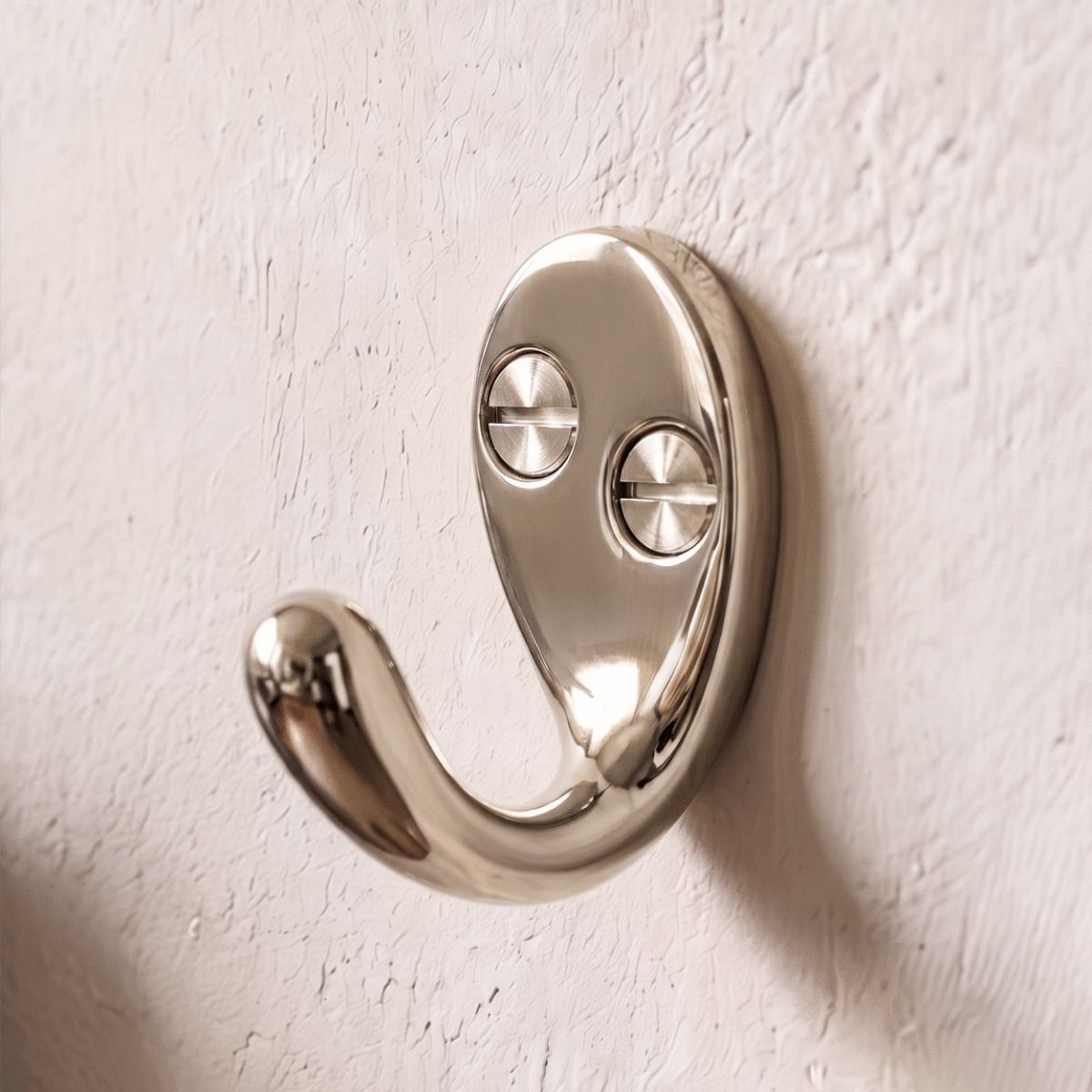 A Polished Nickel Single Pronged Coat Hook Attached to a Textured Home Wall - Digital Illustration 