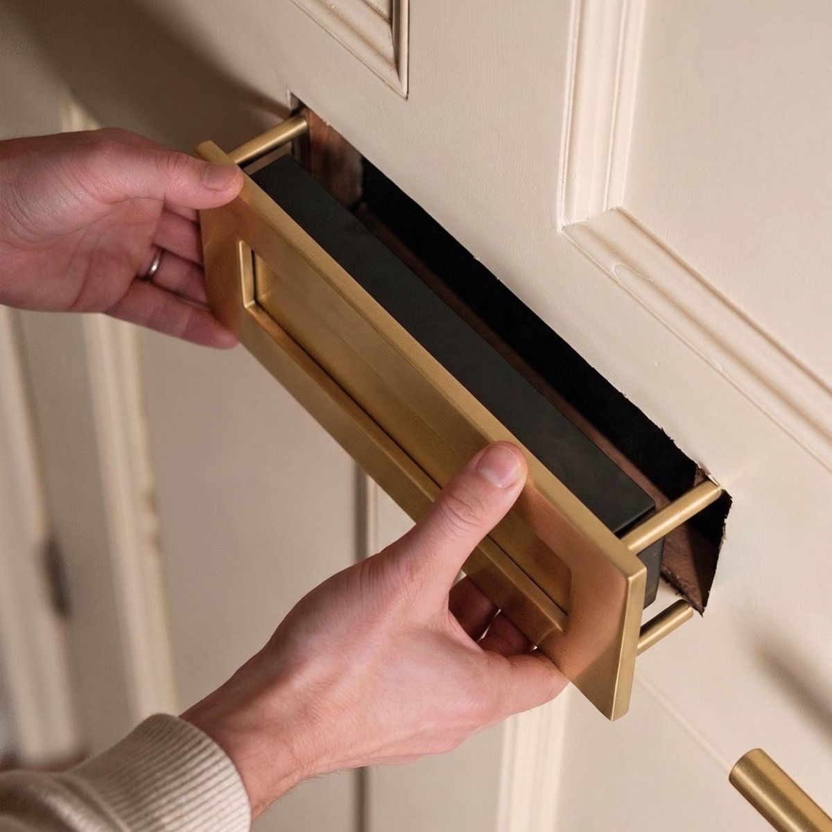 A Satin Brass Traditional Door Letterbox being Mounted onto a White Door - Digital Illustration