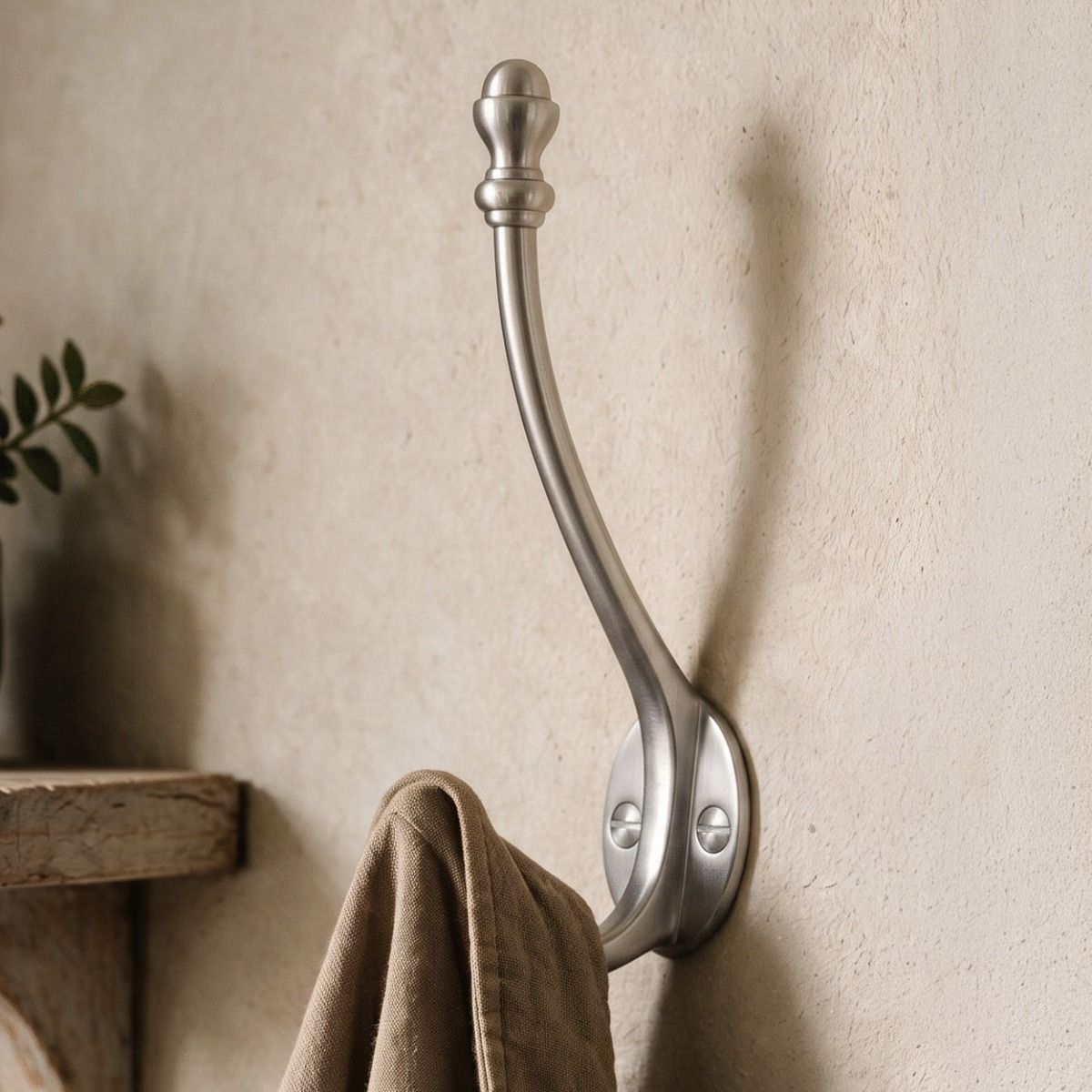 A Satin Chrome Double Pronged Mushroom-Capped Coat Hook Fitted on a Cream Coloured Wall in an Interior Setting - Digital Illustration 