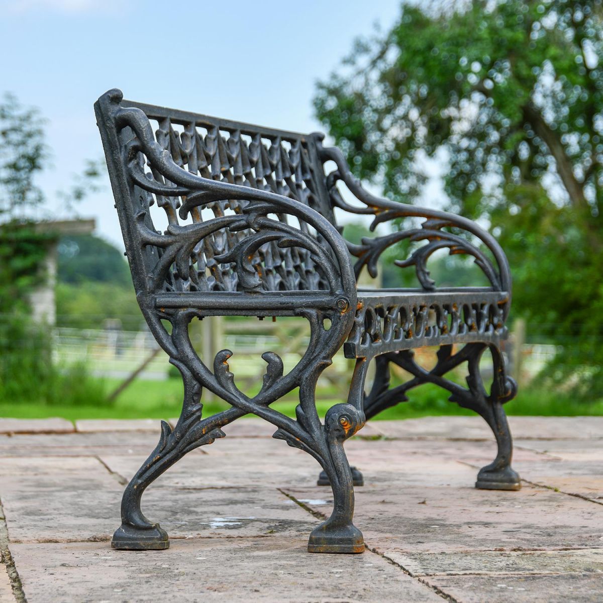View of the Side of the Aged Black "Quatrefoil" Victorian Cast Iron Two Seat Bench View of the Side of the Aged Black "Quatrefoil" Victorian Cast Iron Two Seat Bench