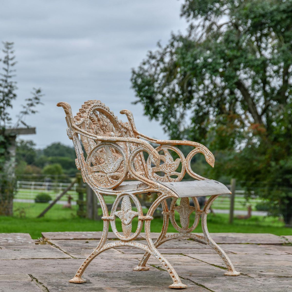 View of the Side of the Aged Cream Cast Iron Dog One Seat Park Bench