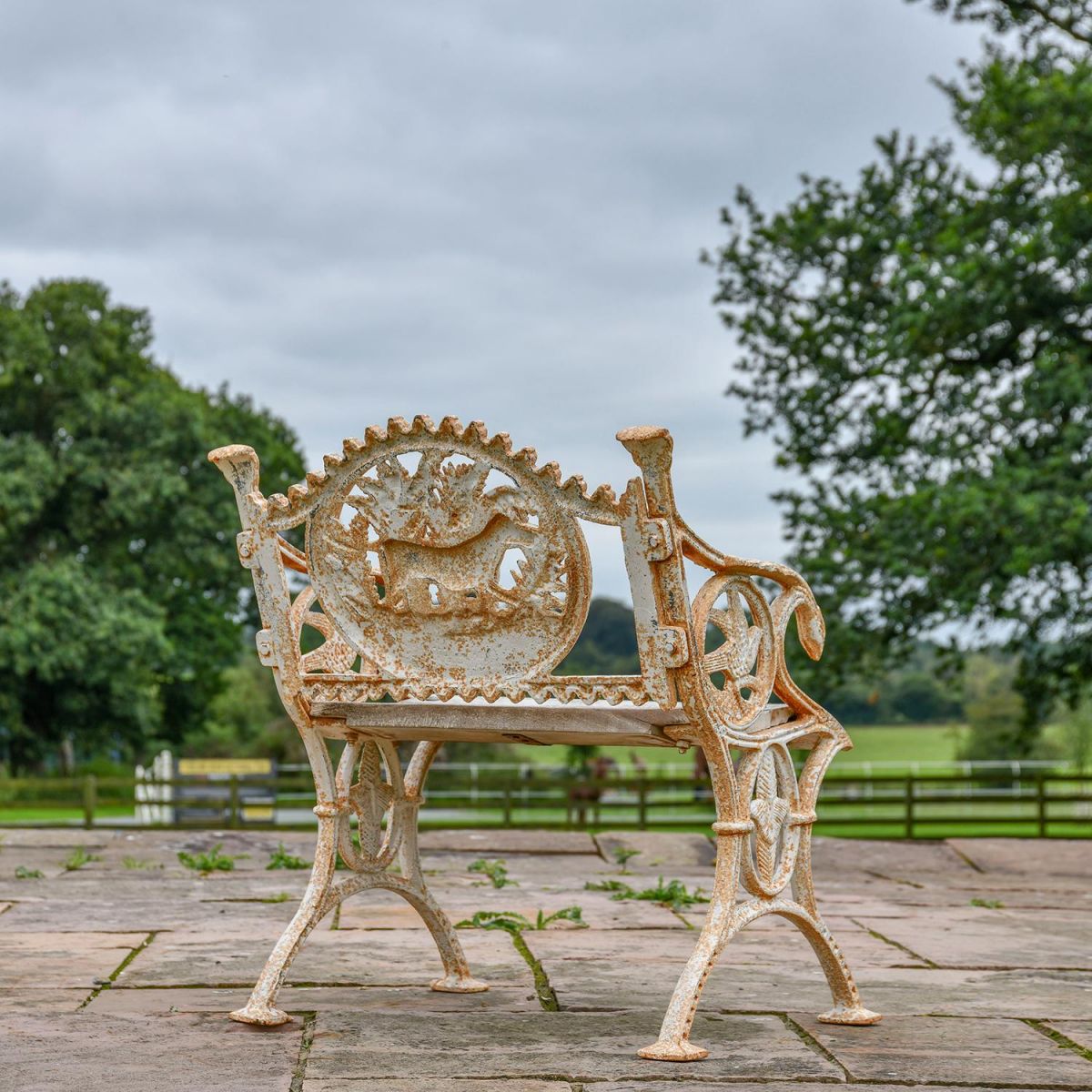 View of the Back of the Aged Cream Cast Iron Dog One Seat Park Bench