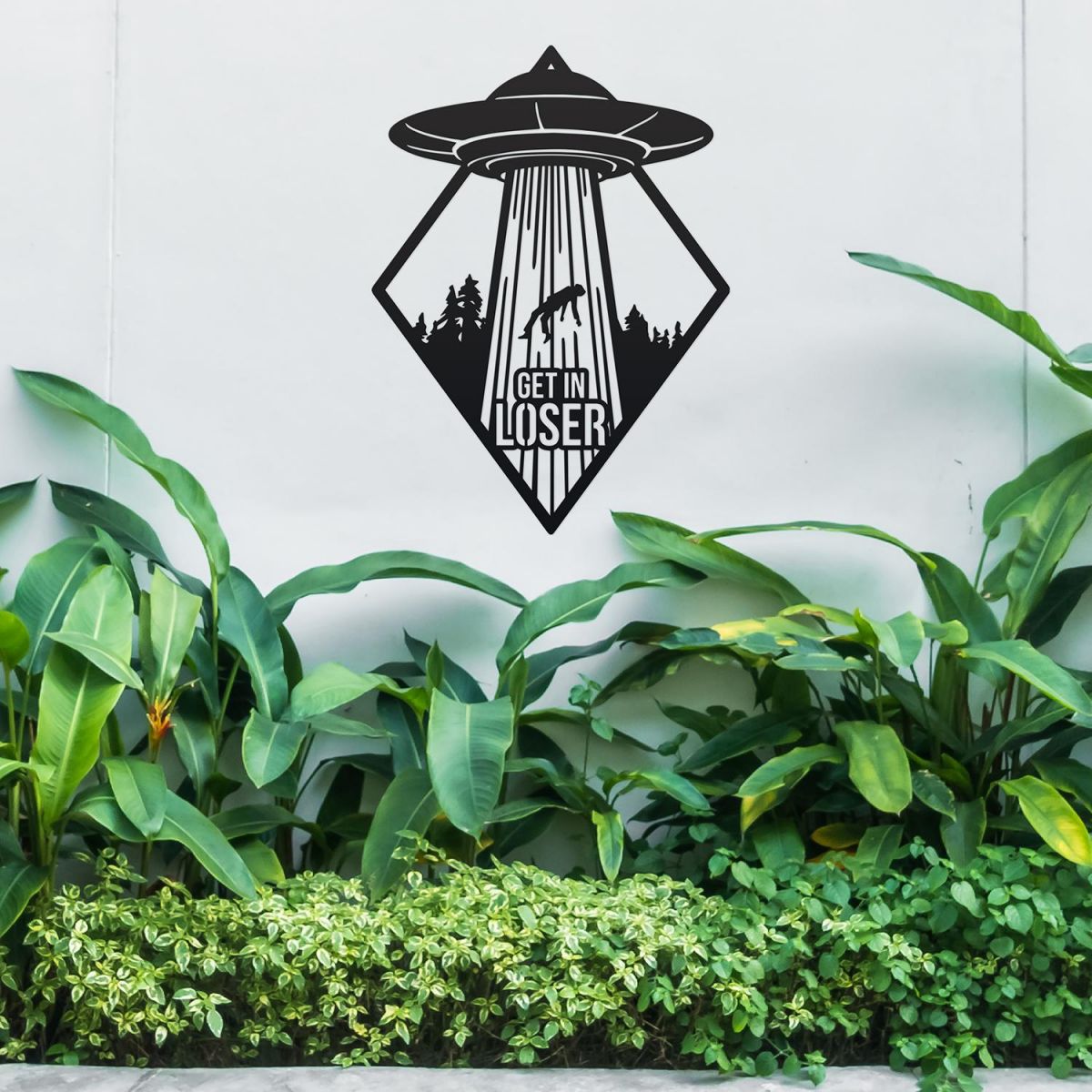 "Get in Loser" Alien Wall Art Above a Bush Outdoors