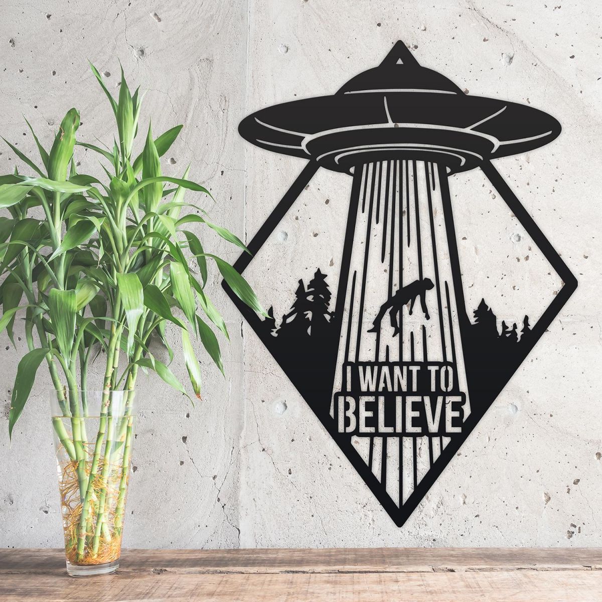 "I Want to Believe" Alien Wall Art Above a Bush Outdoors