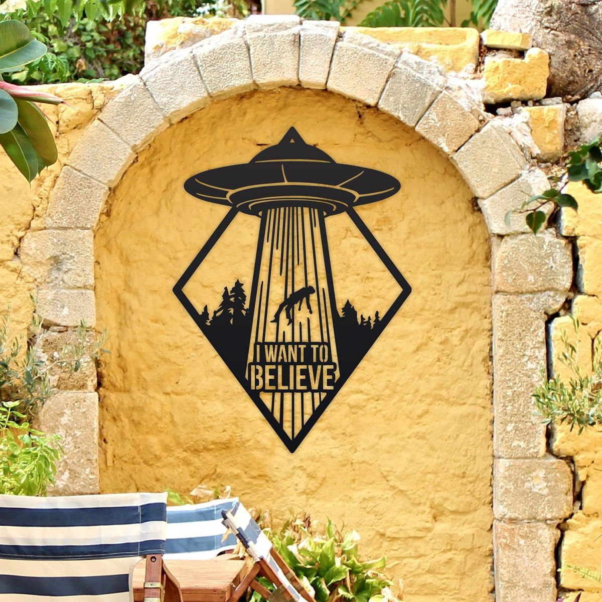 "I Want to Believe" Alien Wall Art on a Yellow Brick Wall in the Garden