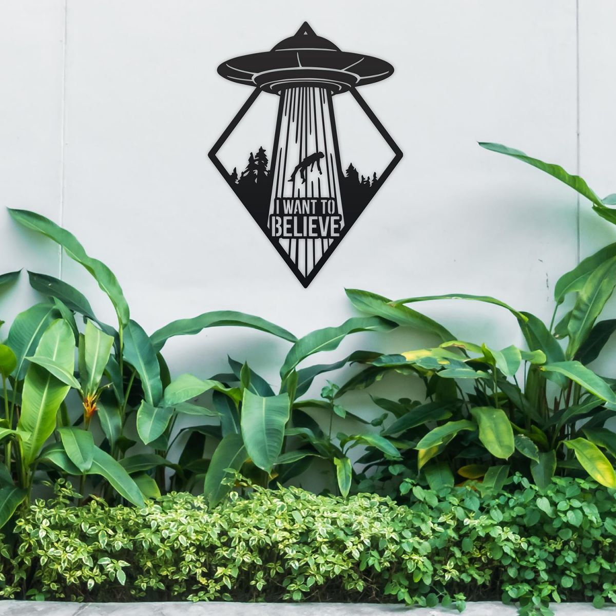 "I Want to Believe"Alien Wall Art in Situ Above Bushes in the Garden