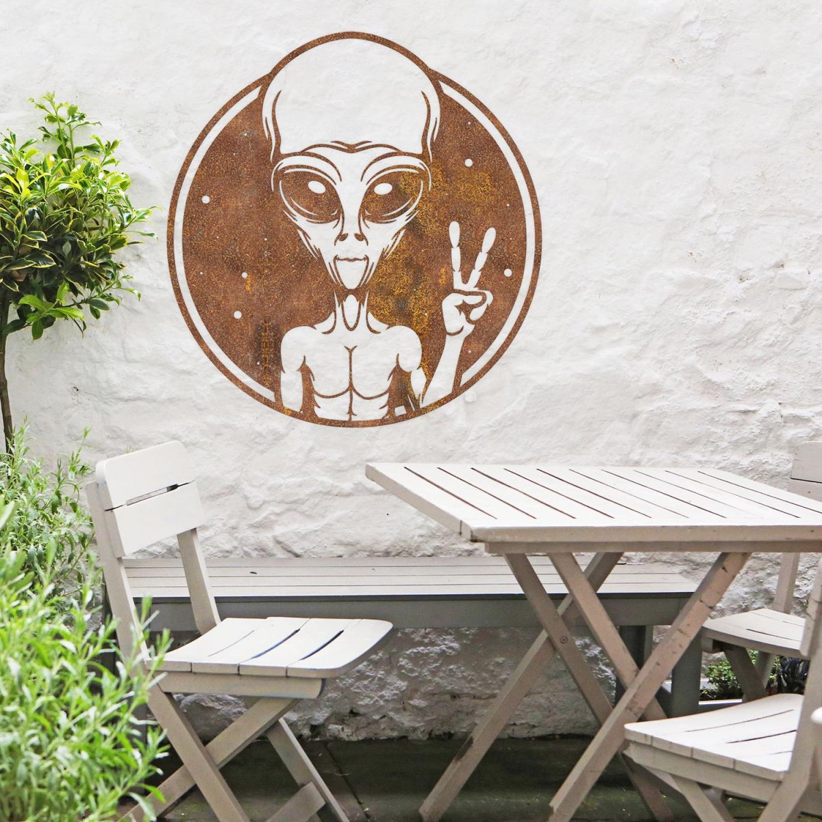 Peace Sign Alien Wall Art in Situ Above a Wooden Garden Furniture Set Peace Sign Alien Wall Art in Situ Above a Wooden Garden Furniture Set