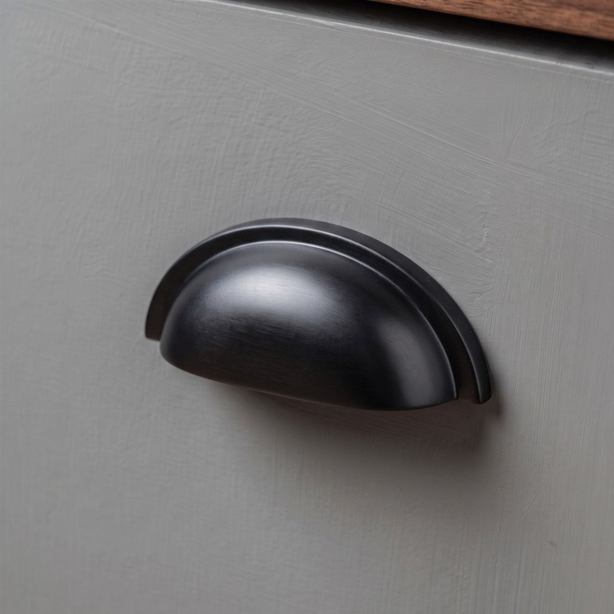 An Art Deco Concealed Cup Drawer Pull in Aged Bronze Shown Close up as Part of a Kitchen Renovation Project for a Set of Drawers - Digital Illustration