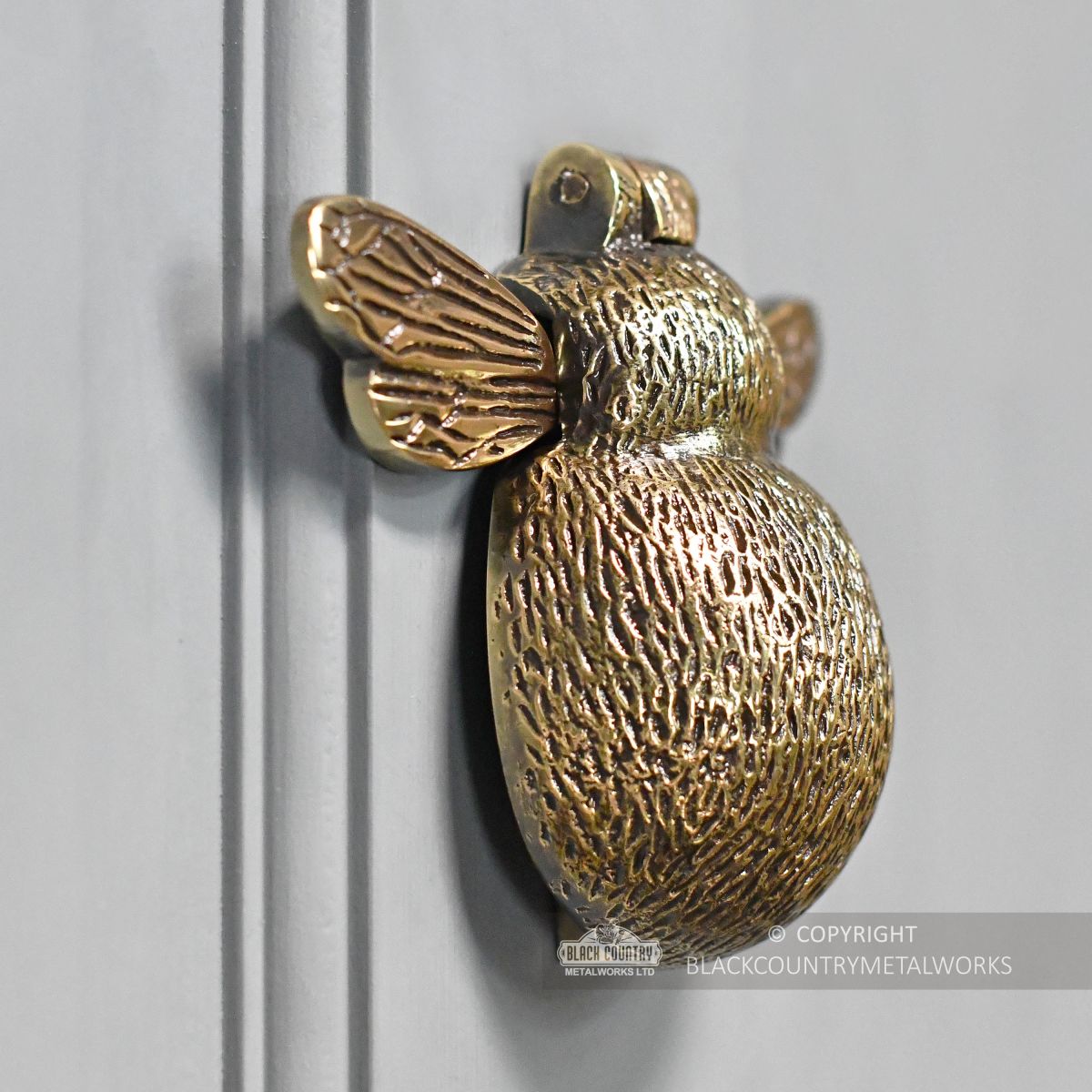 Side view of brass bee door knocker