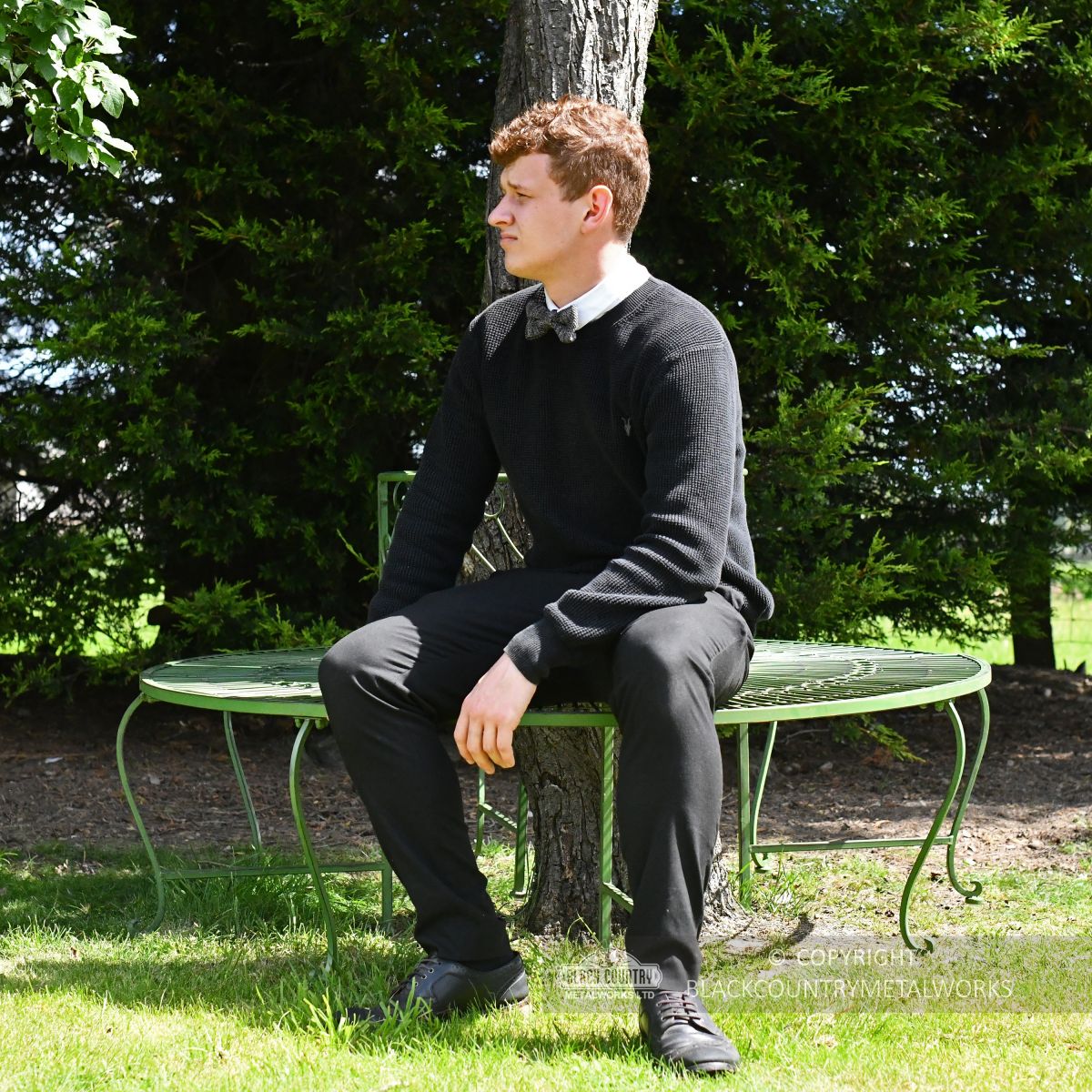 Young man sitting on garden tree seat
