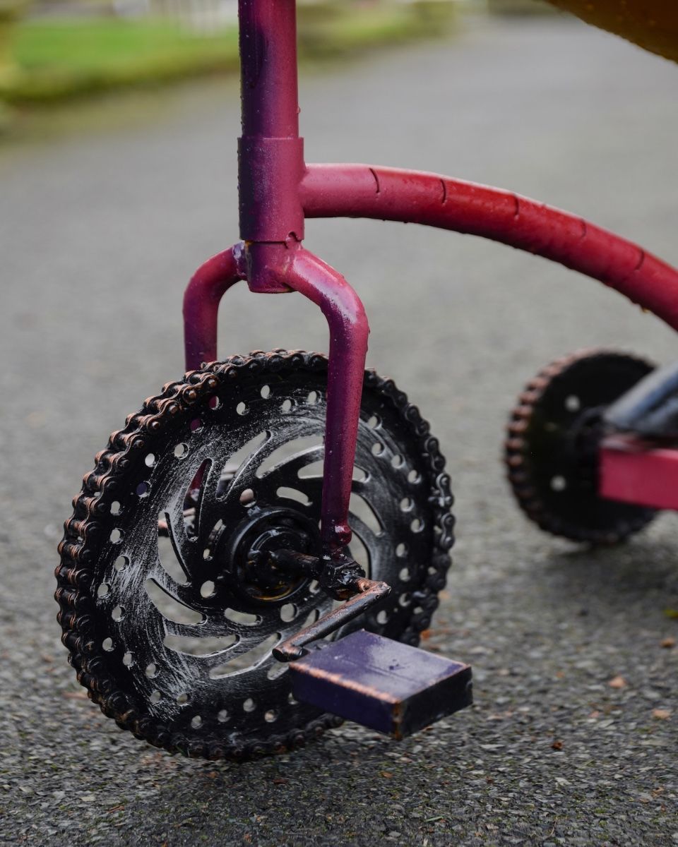 ‘Freewheeler” the Upcycled Metal Giraffe Garden Sculpture on a Tricycle close up of front wheel made from gears and chains