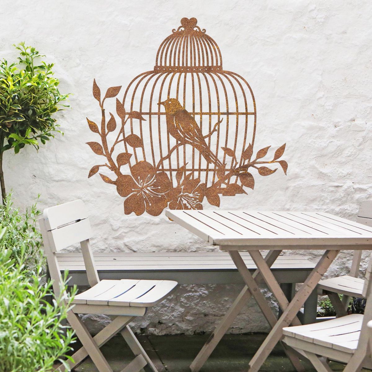 Bird Cage Wall Art in the Garden Above a Wooden Table & Chair Set Bird Cage Wall Art in the Garden Above a Wooden Table & Chair Set