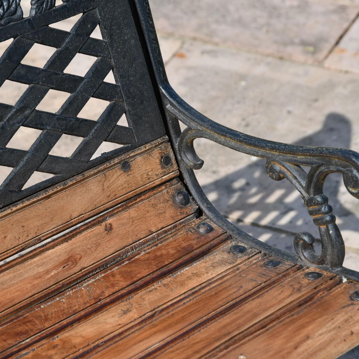 Close up of aged black cast iron & wood garden bench