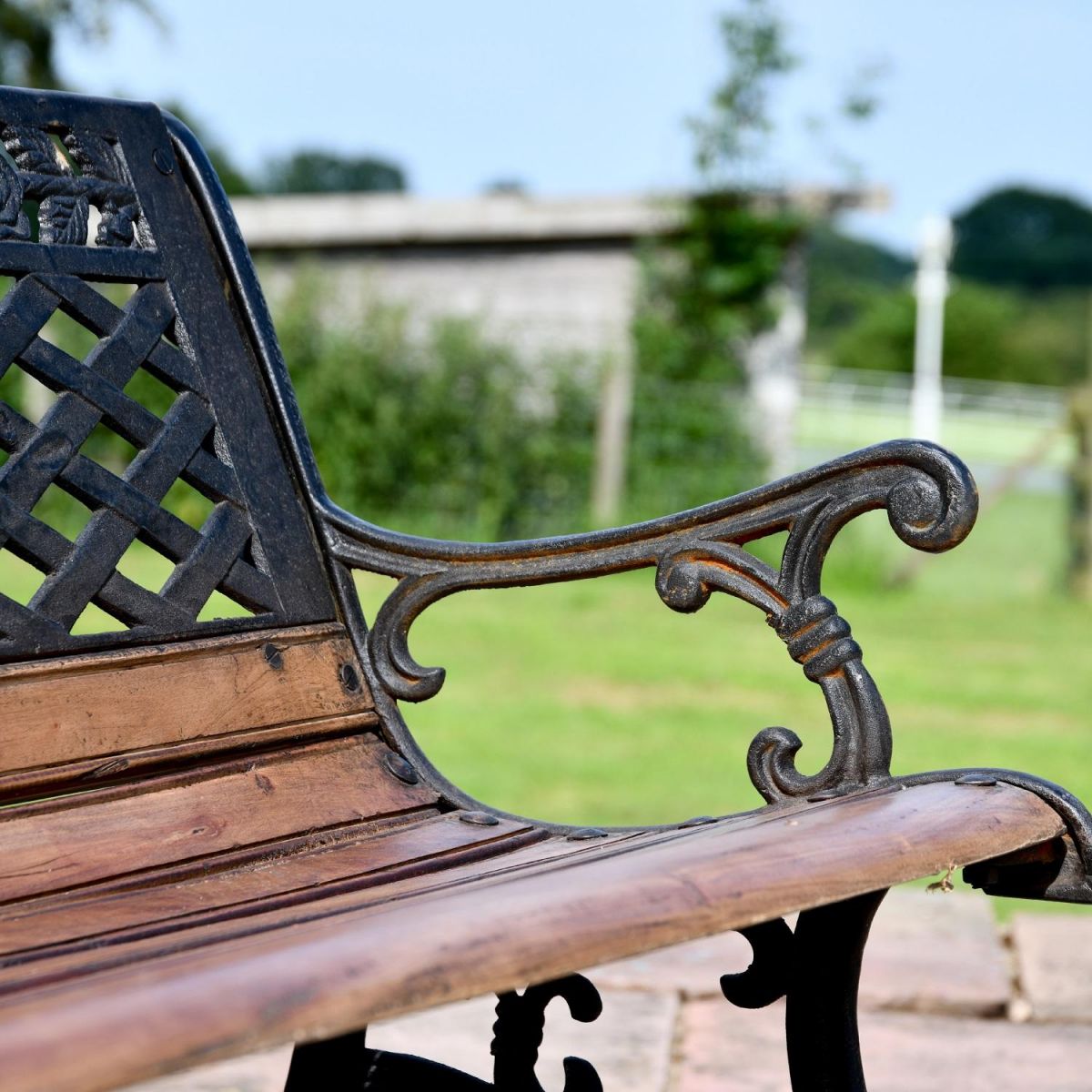 Close up of Aged Black Cast Iron & Wood Garden Bench in Situ