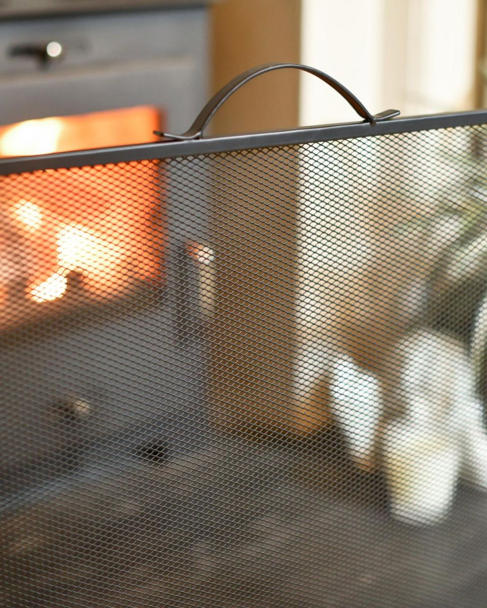 Close Up Of Black Contemporary Curved Fire Guard with Handle Handle In A Fireplace Setting Close Up Of Black Contemporary Curved Fire Guard with Handle Handle In A Fireplace Setting